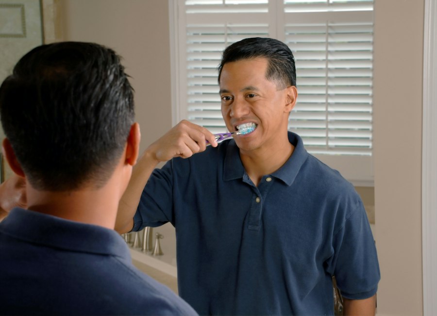 A man brushing his teeth at a bathroom mirror